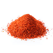 En hög med rött pulver av capsicum som ligger på en bänk mot en vit bakgrund En hög med rött pulver av capsicum som ligger på en bänk mot en vit bakgrund