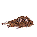 kaffepulver ligger uthallt på ett bord och toppas av vanliga kaffebonor. Kaffepulvret är coffee scrub mot torr hud