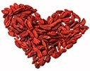 Röda goji bär ligger utspridda i formen av ett hjärta mot en vit bakgrund