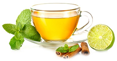 Bild pa en kopp gront te med mint, lime och kanel pa sidan av koppen Bild pa en kopp gront te med mint, lime och kanel pa sidan av koppen