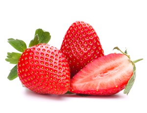 Två hela jordgubbar och en halv jordgubbe ligger lite slarvigt bredvid varandra med blad mot en vit bakgrund