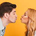 en man och en kvinna lutar sig in for att pussas mot en gul bakgrund