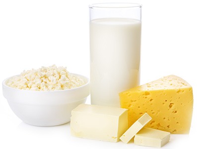 en vit skal med popcorn, ett glas mjolk, smor och en ost mot en vit bakgrund