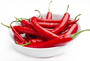 en vit skal med flera roda chilifrukter i mot en vit bakgrund en vit skal med flera roda chilifrukter i mot en vit bakgrund