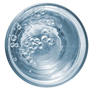 ett glas med vatten med bubblor i ovanifran mot en vit bakgrund