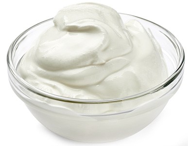 en genomskinlig glasskal med kramig yoghurt i, mot en vit bakgrund
